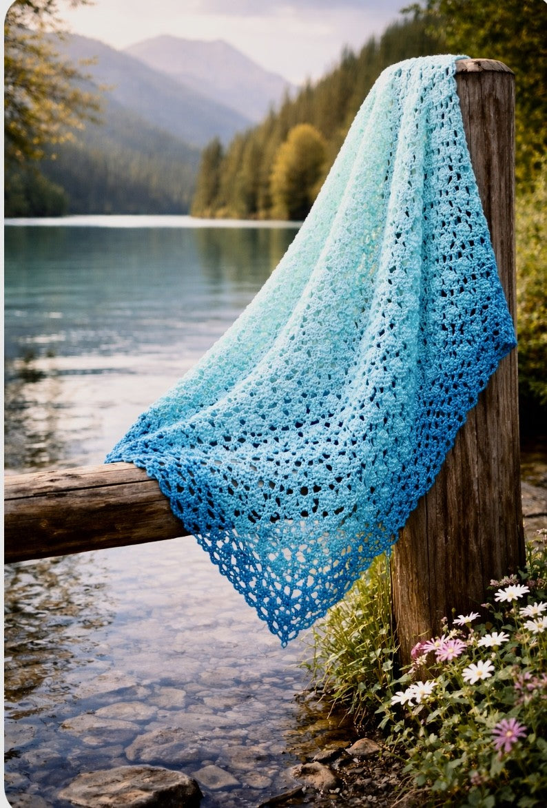 Ombre crochet shawl draped by the water's edge, showing gradient color detail